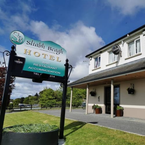 Sliabh Beagh Hotel entrance with signage, white building, garden view, and blue sky in Monaghan, Ireland