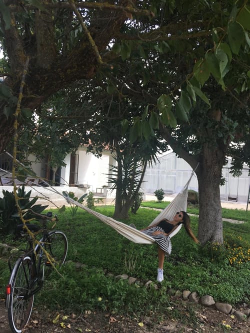 Donna che si rilassa in un'amaca sotto gli alberi all'Agriturismo Il Pomo d'oro ad Assemini, Italia
