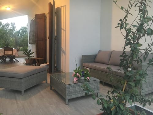 Moderna zona lounge dell'Agriturismo Il Pomo d'oro con mobili in vimini, fiori in vaso e piante decorative ad Assemini