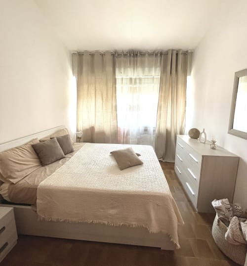 Camera da letto luminosa e minimalista a Varenna by Foot con letto matrimoniale, cassettiera bianca e tende trasparenti con vista sulle montagne