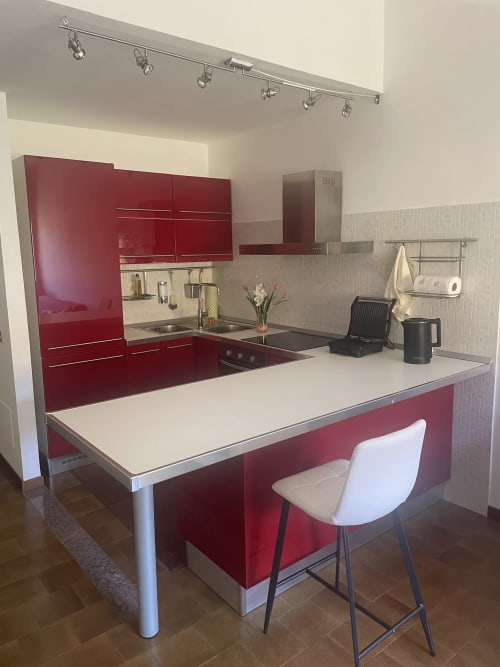 Cucina moderna rossa con isola top bianco e posti a sedere bar nell'appartamento Varenna by Foot in Italia