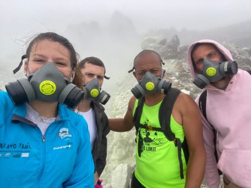 Quatre randonneurs portant des masques de protection dans un paysage volcanique de la Guadeloupe près de Sainte-Rose