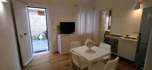 Moderno appartamento open space a Bari Vacation con tavolo da pranzo bianco, TV, cucina e porta con vista sul giardino