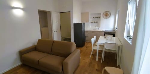 Zona living dell'appartamento vacanze a Bari con divano, tavolo da pranzo, cucina e arredi moderni su pavimento in legno