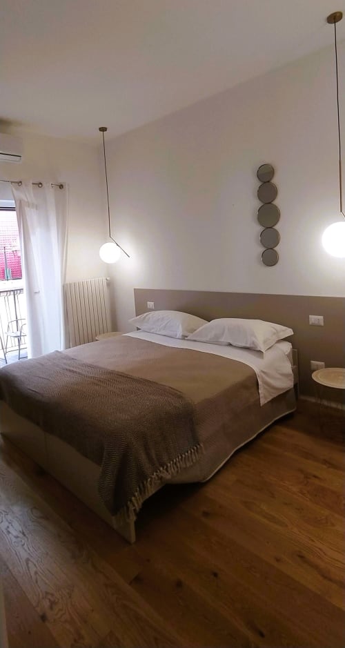 Camera moderna a Bari Vacation con letto matrimoniale, illuminazione a sospensione, specchi a parete e accesso al balcone a Bari, Italia