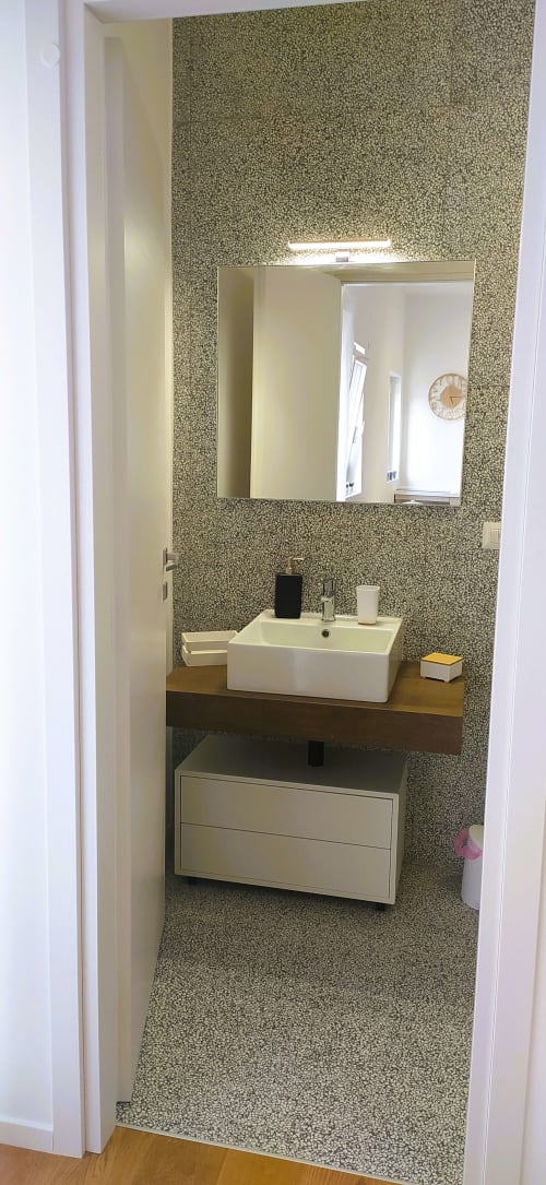 Bagno moderno dell'appartamento vacanze a Bari con carta da parati a texture, lavabo bianco a vessel, specchio e mobile in legno.