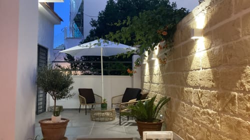 Terrazza dell'appartamento vacanze a Bari con ombrellone, lettini, piante in vaso e muri in pietra a Via Genova 31