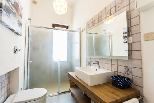 Modern bathroom at Villa Maria with vessel sink, wooden vanity, frosted glass shower, and taupe tile at Sant'Andrea,