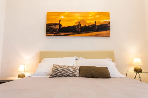 Modern bedroom at Villa Maria with sunset beach canvas art, cream headboard, and warm lighting overlooking Valderice