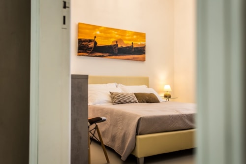 Modern bedroom at Villa Maria with yellow headboard, white bedding, decorative boats artwork, and warm lighting in