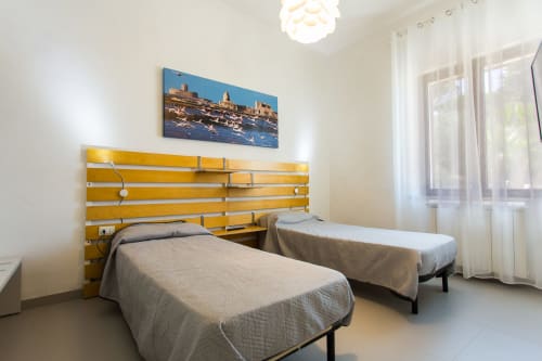 Twin bedroom at Villa Maria with yellow headboard, coastal artwork, and sea views in Valderice, Sicily