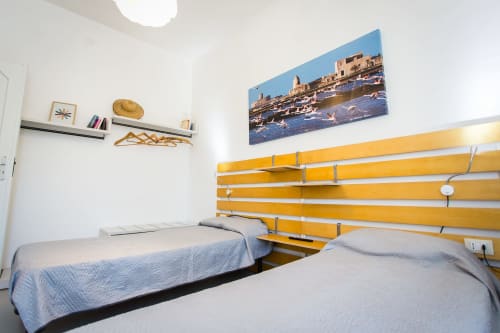 Twin bedroom with yellow headboard and sea view painting at Villa Maria, Sant'Andrea