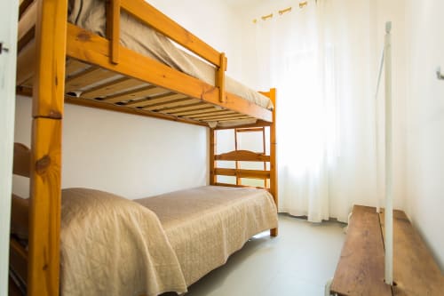 Wooden bunk bed with beige linens in bright room at Villa Maria, Sant'Andrea, Valderice