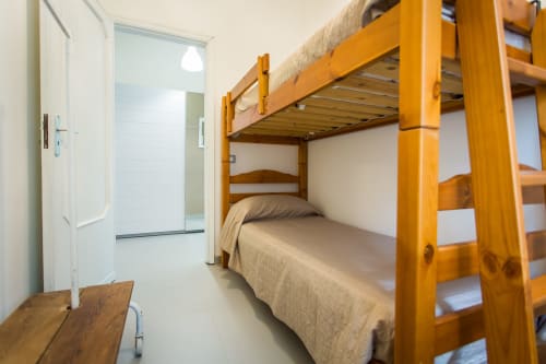 Cozy dorm room at Villa Maria with wooden bunk bed, beige linens, and en-suite bathroom in Sant'Andrea