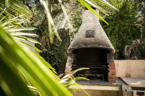 Rustic outdoor pizza oven surrounded by lush greenery at Villa Maria, Valderice Sicily