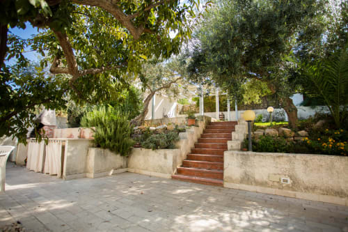Sunny courtyard at Villa Maria with terracotta stairs, mature trees, and Mediterranean garden overlooking Sant'Andrea,
