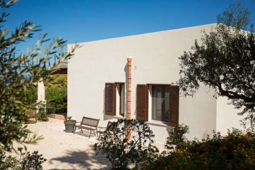 Modern white villa with wooden shutters, patio seating, and Mediterranean garden at Villa Maria, Sant'Andrea Valderice