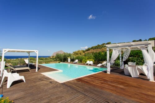 Luxury villa pool with sea view, wooden deck, white pergolas, and loungers in Sant'Andrea, Valderice