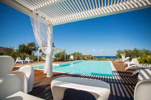 Luxury poolside area at Villa Maria with turquoise infinity pool, white pergola, loungers, and Mediterranean sea view in