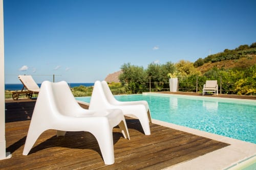 White lounge chairs by turquoise pool at Villa Maria, Sant'Andrea overlooking Mediterranean Sea