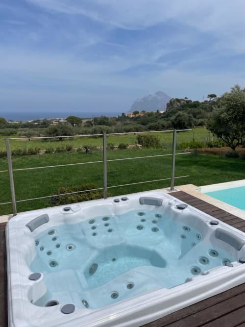 Hot tub overlooking green lawn and sea at Villa Maria, Sant'Andrea Valderice Sicily