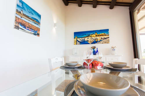Modern dining room at Villa Maria with Mediterranean coastal artwork, white table settings, and sea views in Sant'Andrea,