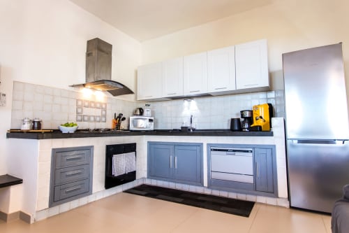 Modern kitchen with white cabinets, stainless steel appliances, and black countertops at Villa Maria Finestra sul Mare,