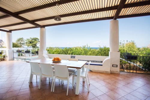 Beachfront terrace with dining table, white chairs, pergola, and sea views at Villa Maria, Sant'Andrea, Sicily