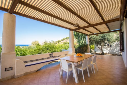 Covered terrace with dining table overlooking Mediterranean Sea at Villa Maria, Sant'Andrea, Sicily