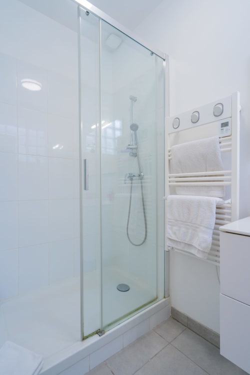 Salle de bain moderne avec douche à l'italienne, porte-serviettes chauffant et carrelage blanc à l'hôtel Room In Toulouse
