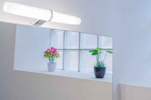 Miroir de salle de bain moderne avec éclairage LED brillant et plantes en pot à l'appartement Room In Toulouse