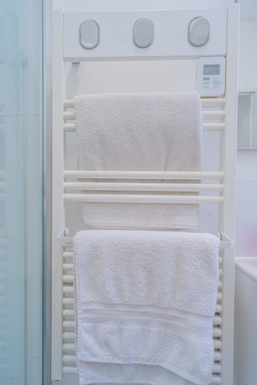 Sèche-serviettes blanc avec serviettes moelleuses et thermostat numérique dans la salle de bain d'un appartement à Toulouse