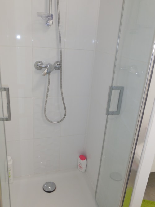 Douche moderne avec robinetterie chromée, pomme de douche amovible et carrelage blanc à l'appartement Room In Toulouse