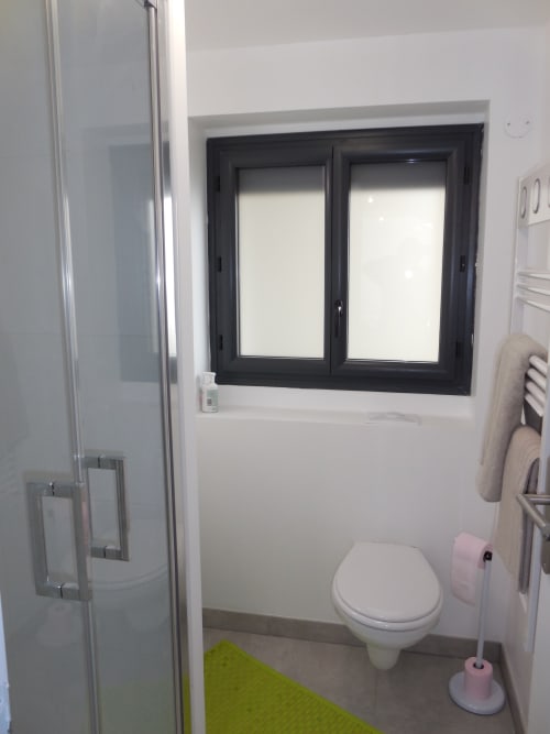 Salle de bain moderne avec toilettes, douche, fenêtre et équipements à l'appartement Room In Toulouse à La Salvetat-Saint-Gilles