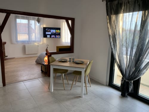 Salle à manger moderne à Toulouse avec table blanche, vue sur la ville dans un miroir, télévision écran plat et accès au balcon
