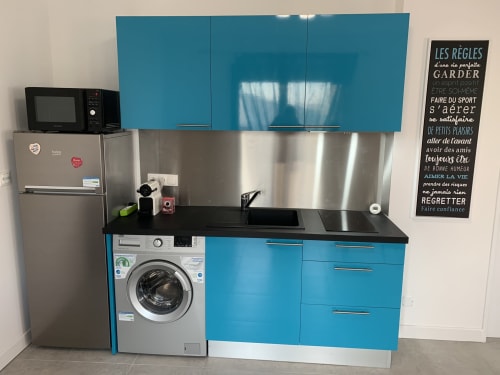 Cuisine turquoise moderne avec électroménagers en acier inoxydable et lave-linge à Toulouse