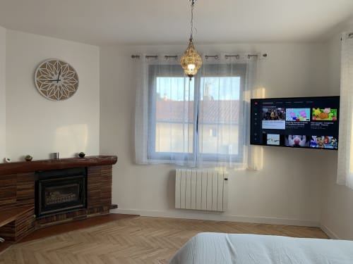 Appartement moderne à Toulouse avec cheminée, télévision écran plat, horloge murale géométrique et balcon vue sur la ville