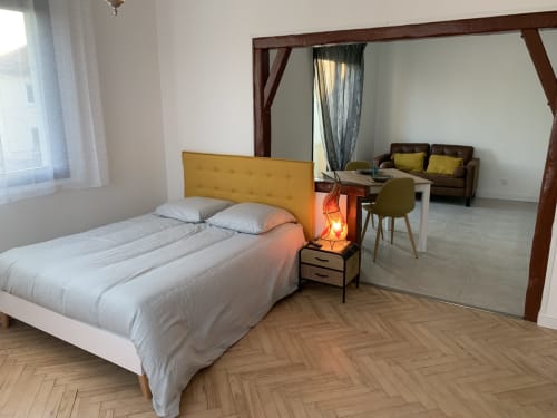 Chambre moderne avec tête de lit moutarde, miroir, espace bureau et séjour dans un appartement toulousain