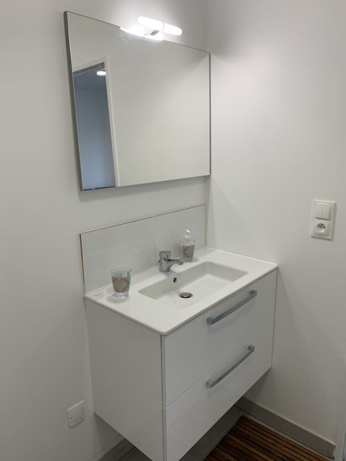 Meuble salle de bain blanc moderne avec lavabo, miroir et éclairage intégré à l'appartement Room In Toulouse