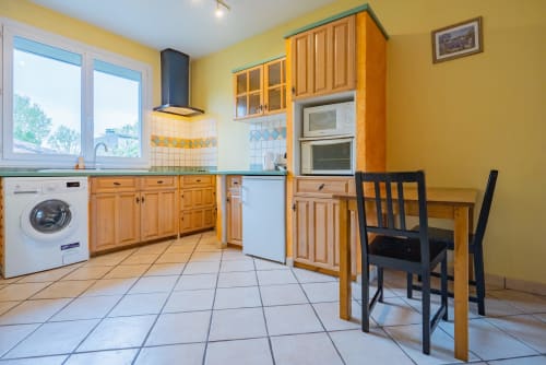 Cuisine jaune lumineux dans un appartement toulousain avec meubles en bois, électroménagers modernes et table à manger