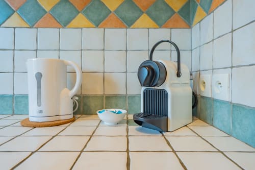 Comptoir de cuisine à Room In Toulouse avec bouilloire, cafetière et bol sur carrelage mosaïque