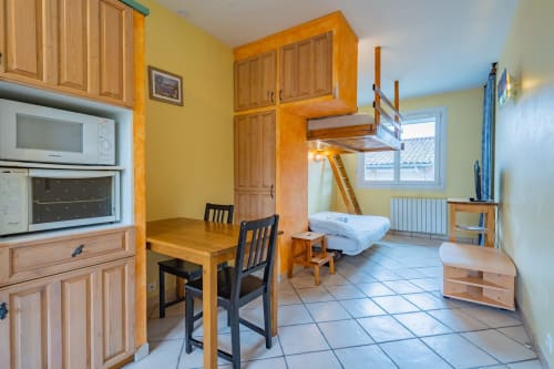 Studio lumineux à Toulouse avec mobilier en bois, kitchenette, coin repas et lit mezzanine avec vue sur la ville