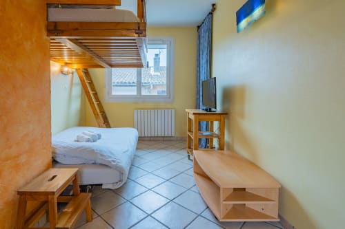 Chambre confortable à Toulouse avec lit mezzanine, mobilier en bois, téléviseur et vue sur la ville depuis la fenêtre