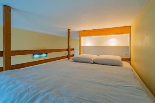 Chambre moderne à Room In Toulouse avec lit en bois, lits jumeaux, murs jaunes et vue sur la ville à La Salvetat-Saint-Gilles