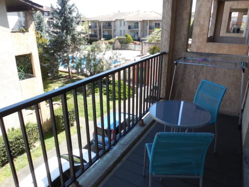 Balcon avec chaises et table bleues surplombant la piscine de l'hôtel Room In Toulouse à La Salvetat-Saint-Gilles