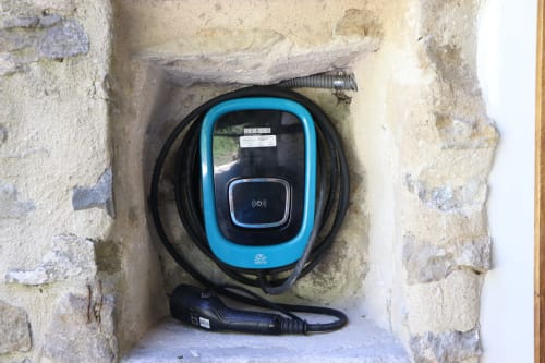 Estación de carga para vehículos eléctricos montada en muro de piedra del hotel Casa Lafuente en Lukiano, Araba