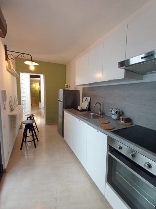 Cucina moderna a Bari con mobili bianchi, elettrodomestici in acciaio inox e parete accent verde oliva