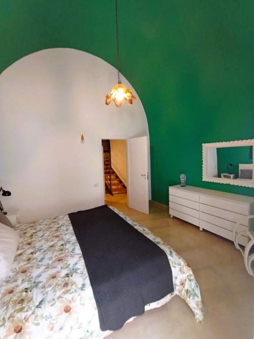 Camera da letto moderna della villa vacanzale di Bari con soffitto a cupola bianca, parete verde accent, lampada a sospensione e biancheria floreale