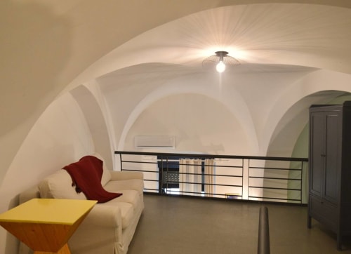 Camera da letto con volta moderna nella villa vacanze di Bari, con divano color crema, tavolo giallo e illuminazione a soffitto arcuato