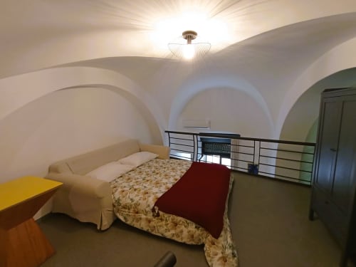 Ampia camera da letto nella villa di Bari con soffitti a volta bianchi, letto, divano color crema e servizi moderni